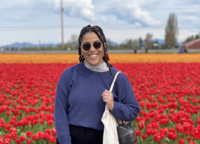 Writer Grace Dunbar-Miller stands in front of a field of red tulips.