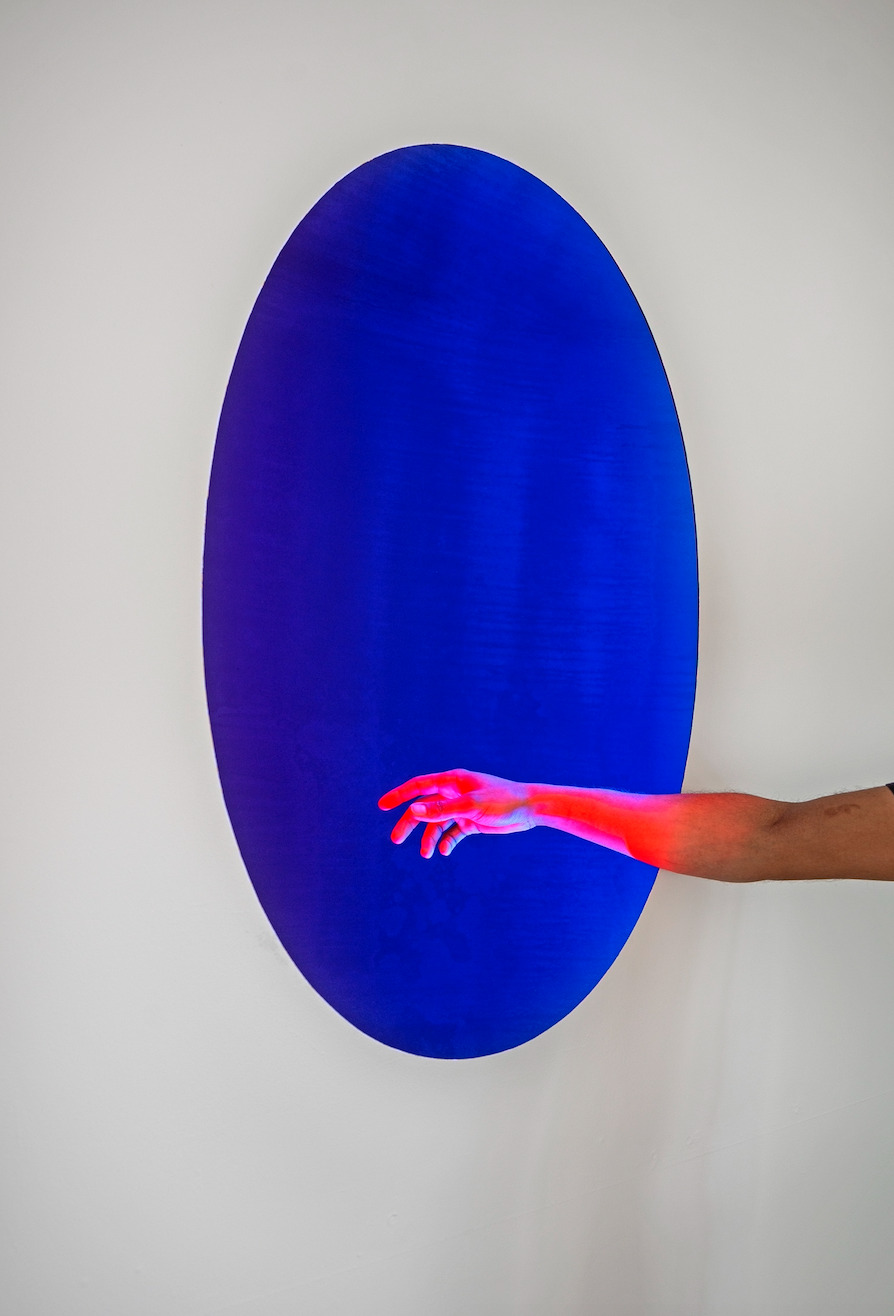 Image from Henry Jackson Spieker's "Void." A hand in front of a blue circle.