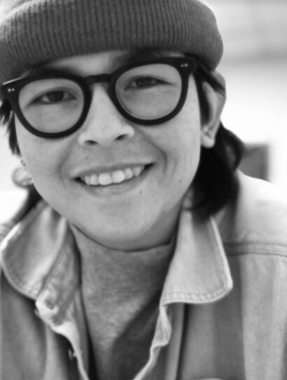 Poet Alina Nguyen in glasses and wearing a hat, black and white photograph