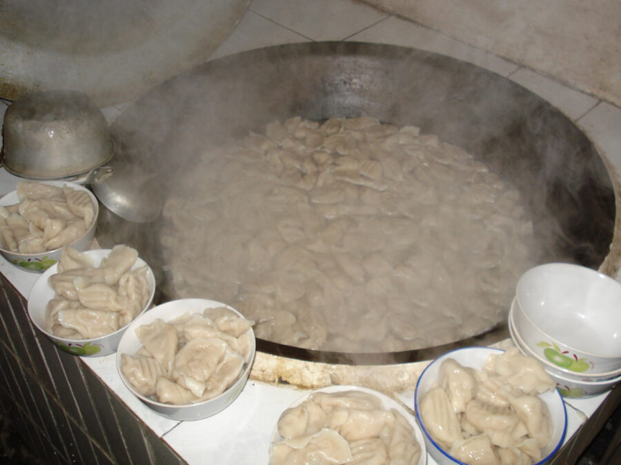 Diana Xin's family dumplings. Plump dumplings on plates surround a steaming wok.