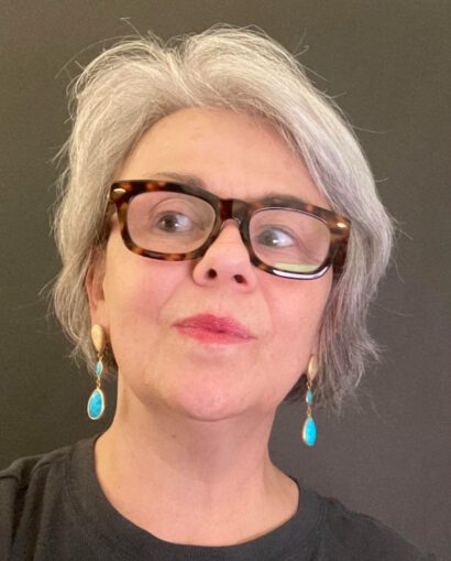 Writer Melanie Bryant in tortoise shell eyeglasses and blue earrings.