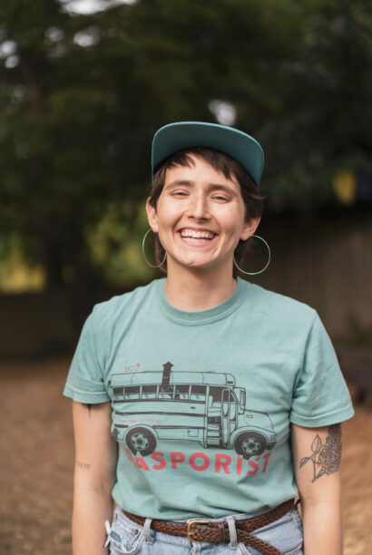 Poet Shelby Handler smiling in a green t-shirt and baseball cap