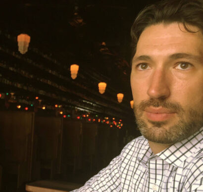 Poet Andrew Nurkin in a plaid shirt and beard, with dark brown hair