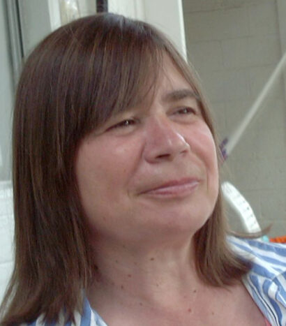 Poet Judy Kaber smiling with light brown hair and a blue striped shirt