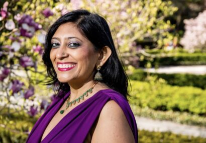 Purvi smiling with black hair in a purple shirt