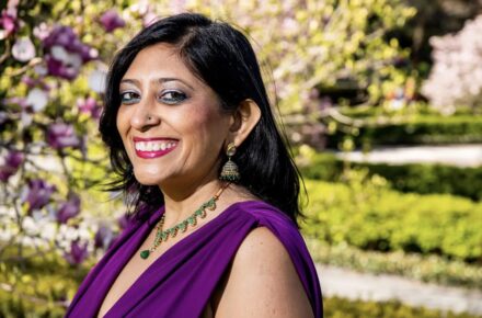 Purvi smiling with black hair in a purple shirt