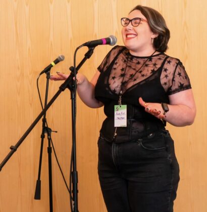 Alex smiling in a black shirt in front of a microphone