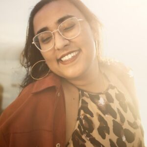 Yaminee smiling in a brown shirt in the sun