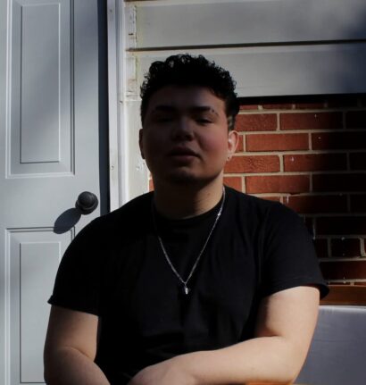 Mercedes in a black t-shirt in front of a brick wall