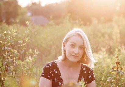 Amanda with blonde hair in front of a field of flowers