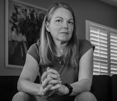 Michelle with medium length hair in a t-shirt, in front of a painting