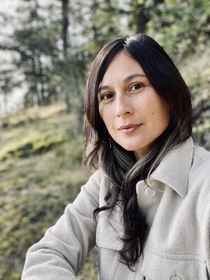Elisabeth Vasquez Hein looks directly at the camera against a hillside landscape.