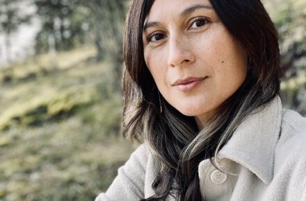 Elisabeth Vasquez Hein looks directly at the camera against a hillside landscape.