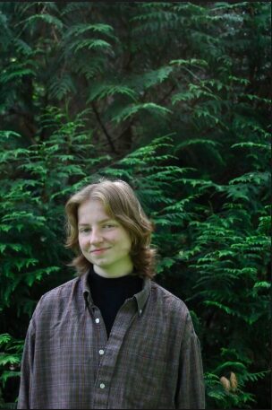 Taylar standing in a lush pacific northwestern forest in front of green ferns