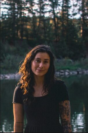 Photo of Emily standing in the late sunlight by a green pond