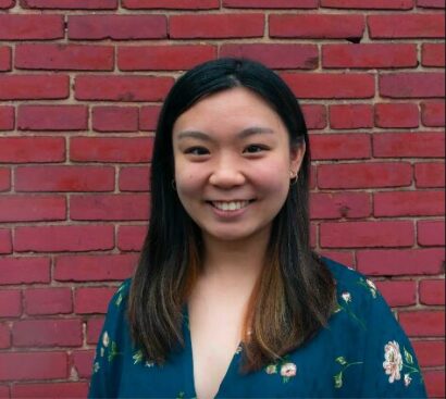 Photo of Victoria Chen smiling in front of a red brick wall in a blue floral blouse