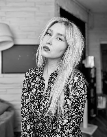 Black and white photo of Amanda posing indoors in a floral blouse