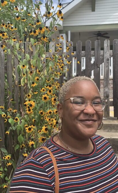 Abeo smiling with glasses in front of flowers